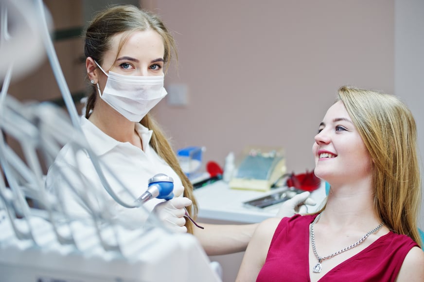 attractive-patient-redviolet-dress-laying-dental-chair-while-female-dentist-treating-her-teeth-with-special-instruments
