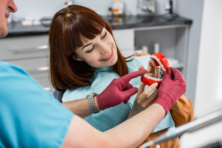 attractive-smiling-young-woman-sitting-dental-chair-stomatology-clinic-with-senior-male-dentist-showing-her-jaw-teeth-sample-healthy-teeth-concept_161094-1239