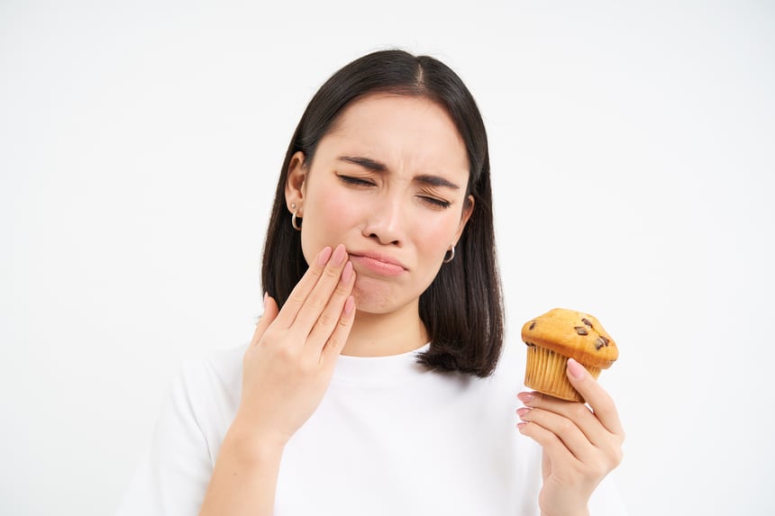 close-up-portrait-asian-woman-with-toothcahe-looks-cupcake-too-sweet-dessert-cant-eat-white-ba
