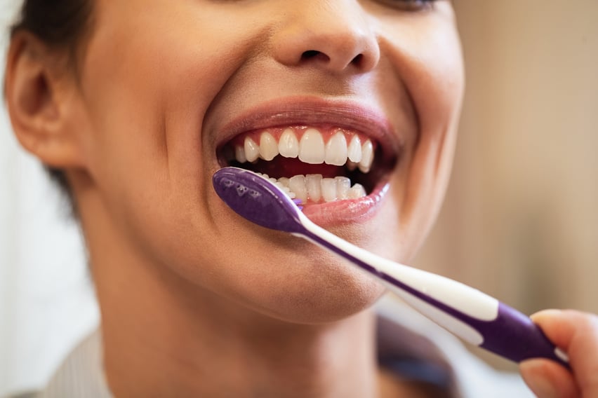 closeup-woman-using-toothbrush-while-brushing-teeth-bathroom