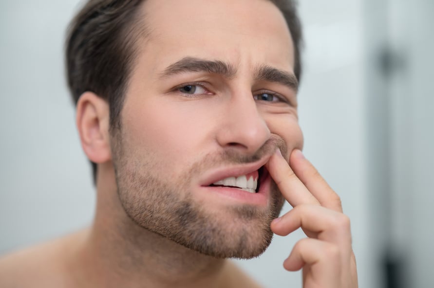 dental-problems-man-checking-his-teeth-looking-disturbed