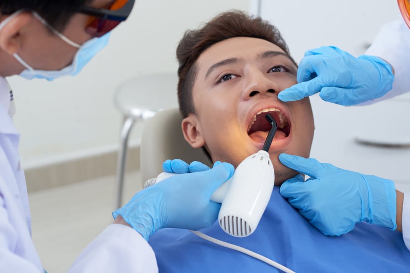 dentist-holding-ultraviolet-light-asian-male-patient-s-tooth-treatment