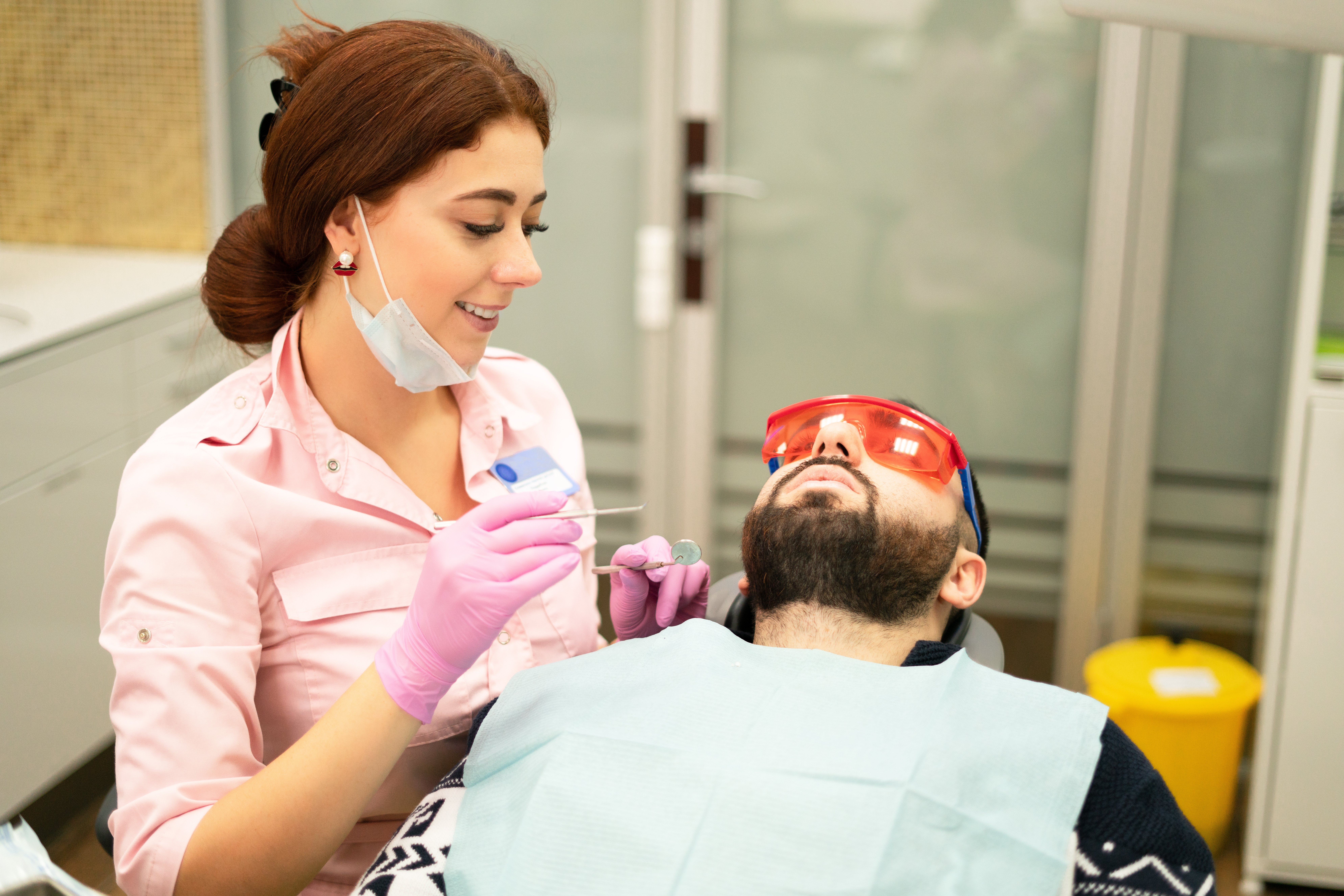 dentist-young-woman-treats-patient-man-doctor-uses-disposable-gloves-mask-hat-dentist-works-patient-s-mouth-uses-professional-tool