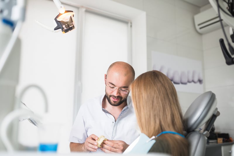 female-patient-front-male-dentist-holding-dental-jaw