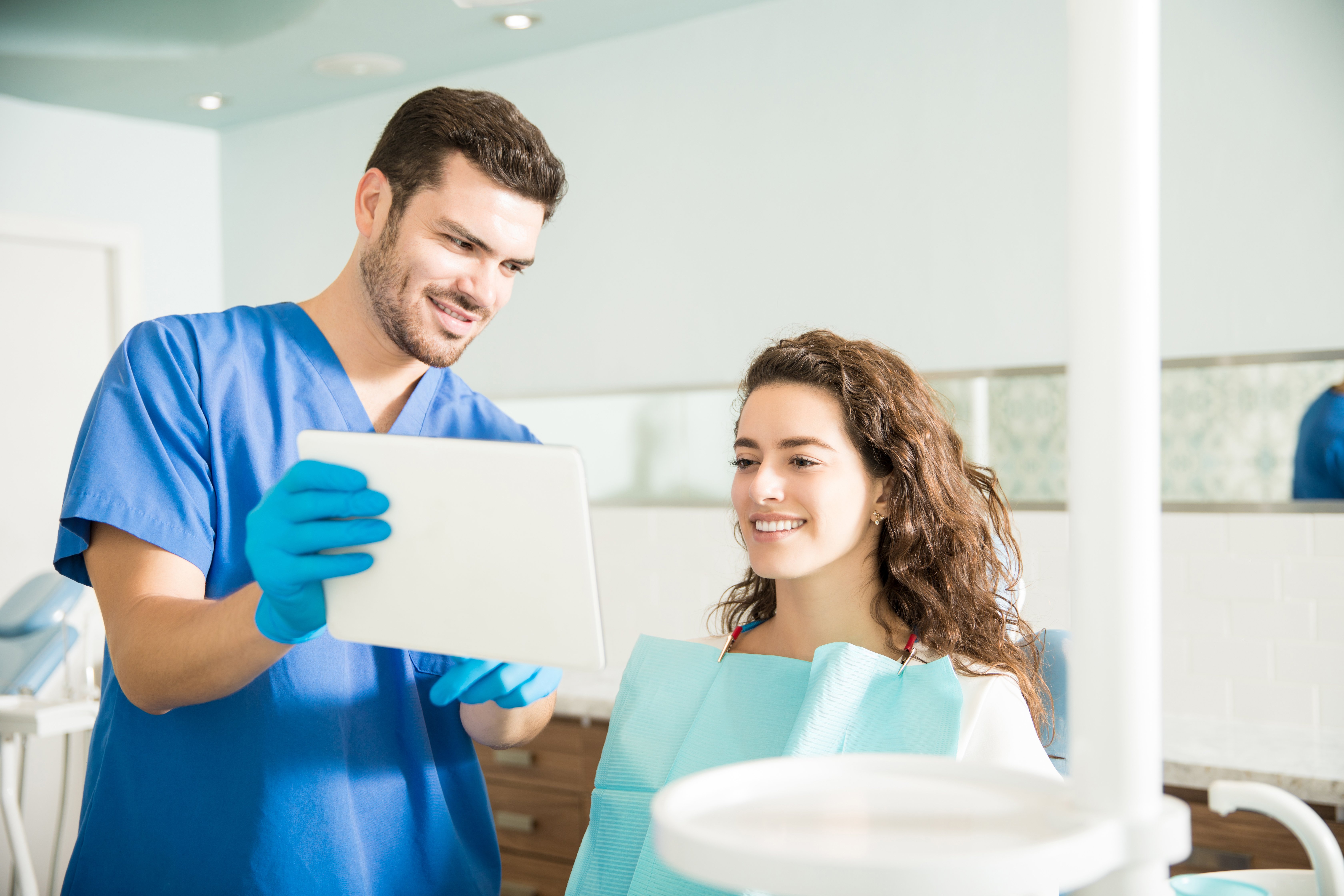 mid-adult-dentist-showing-digital-tablet-female-patient-treatment-dental-clinic-1
