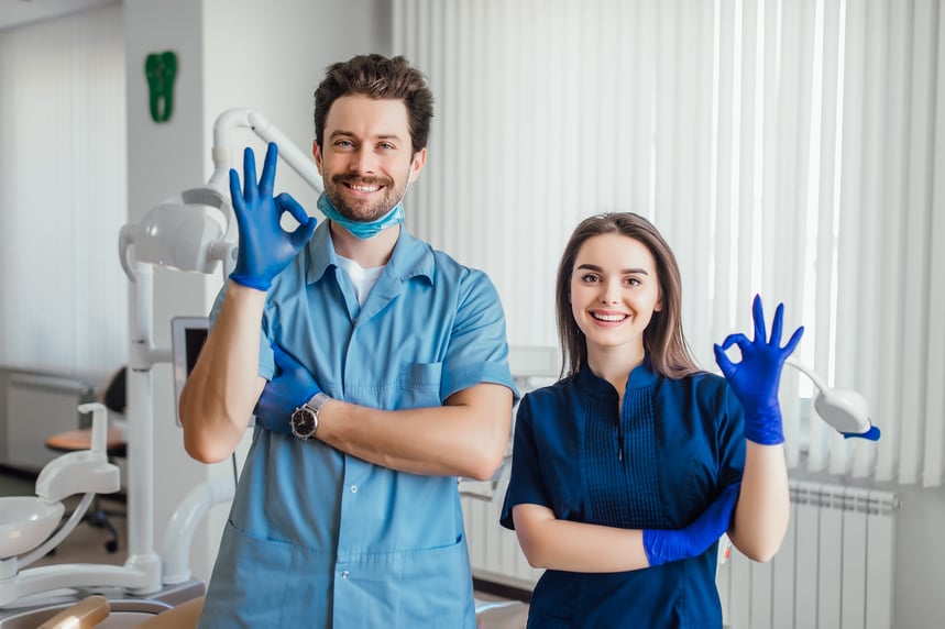 photo-smiling-dentist-standing-with-arms-crossed-with-her-colleague-showing-okay-sign-1