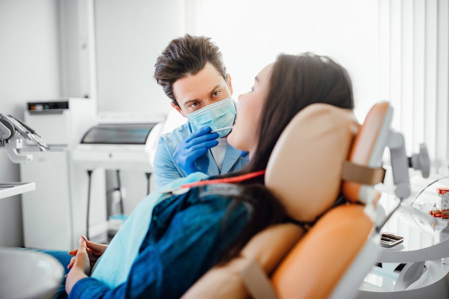 portrait-dentist-blue-mask-working-with-patient-modern-clinic