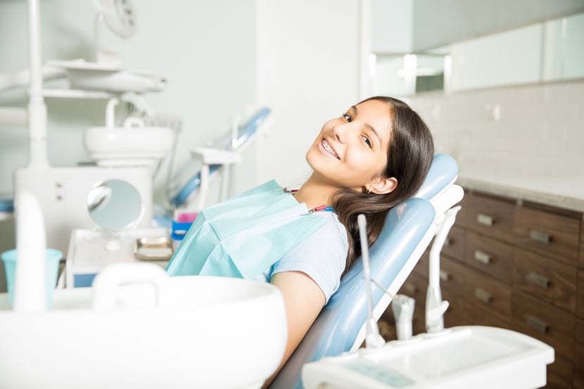 portrait-smiling-teenage-girl-with-braces-sitting-chair-dental-clinic