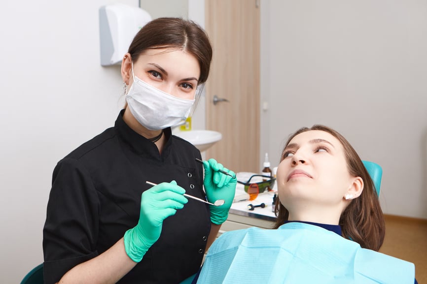 skillful-confident-young-female-dentist-wearing-exam-gloves-white-mask-holding-metal-probe-dental-mirror-ready-examine-oral-cavity-woman-patient-sitting-chair