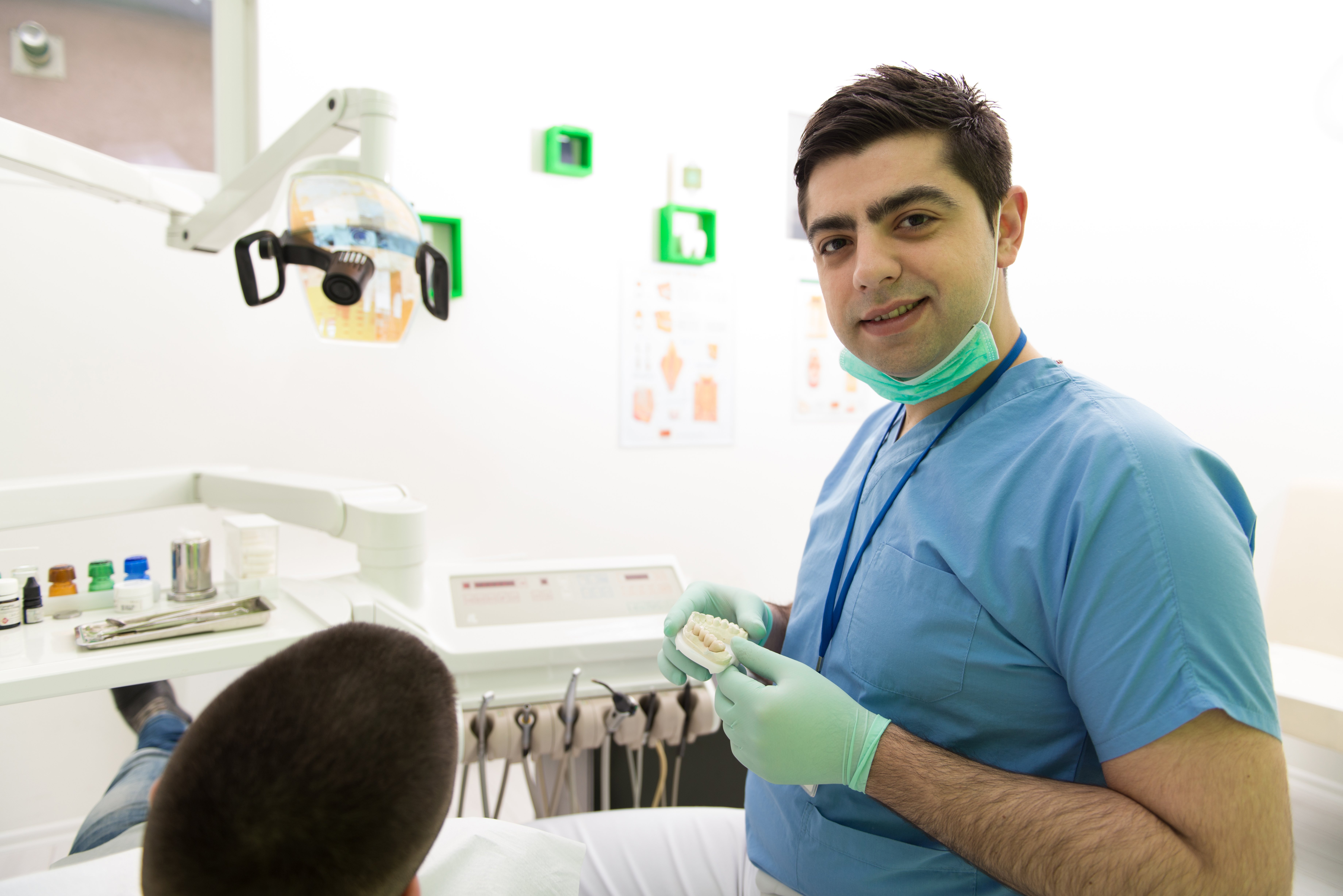 smiling-male-dentist-explaining-artificial-teeth-patient-clinic