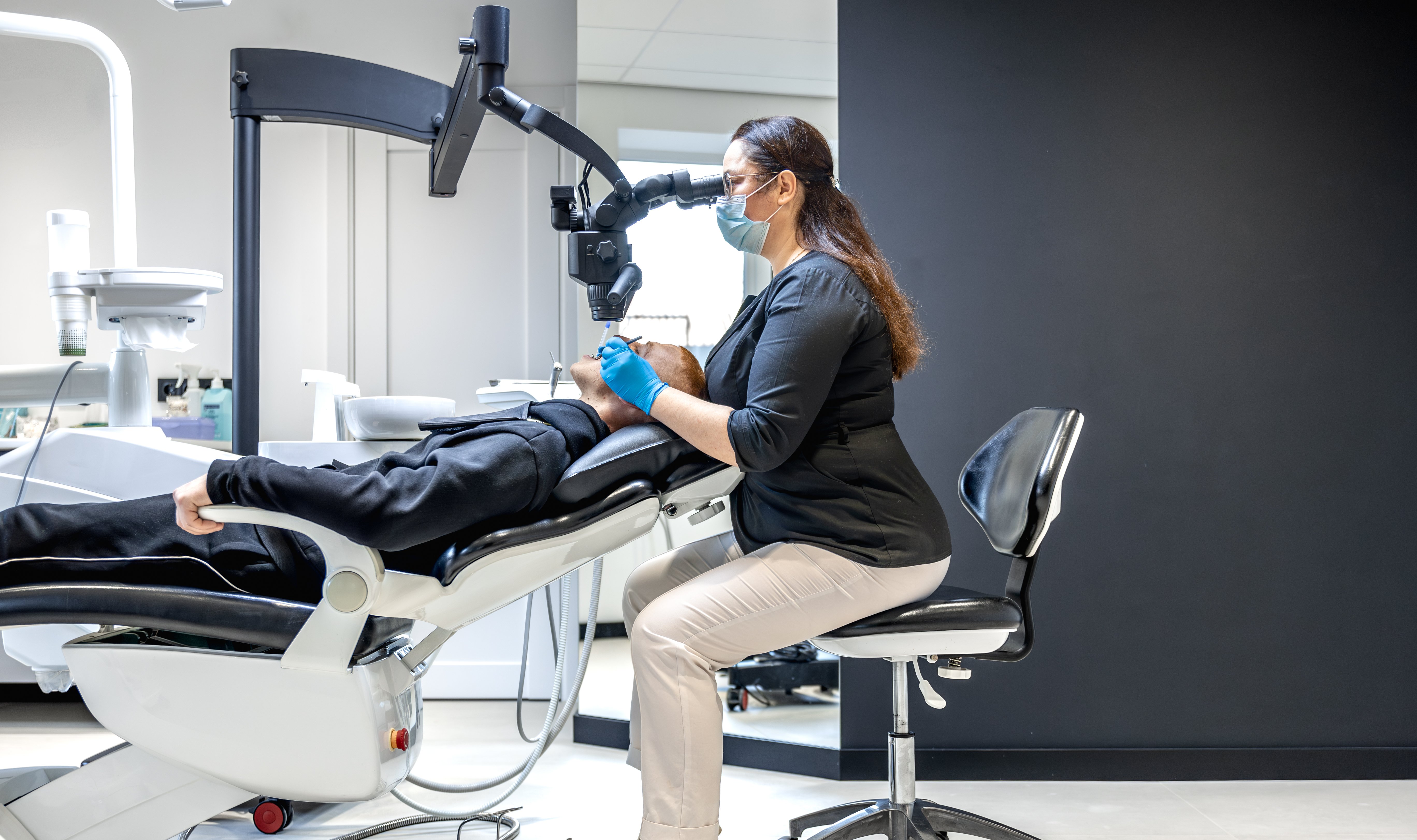young-female-dentist-treating-patients-teeth-with-dental-microscope-dentistry-concept