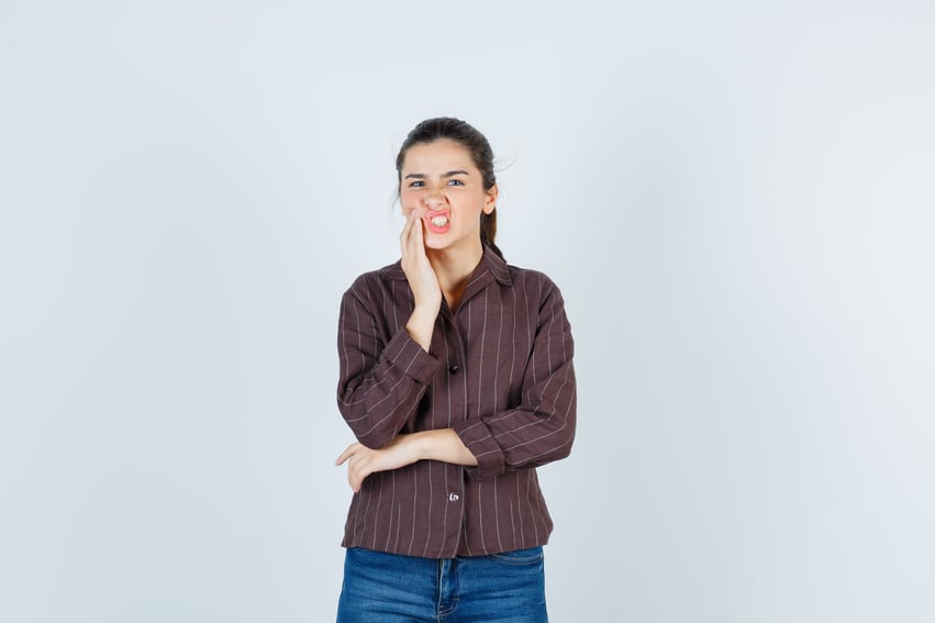 young-woman-with-hand-near-mouth-having-toothache-striped-shirt-jeans-looking-exhausted-front-view
